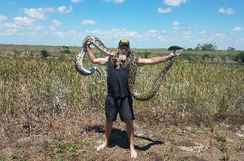 photo of Dustin Crum with the 50th snake caught as part of the Python Elimination Program