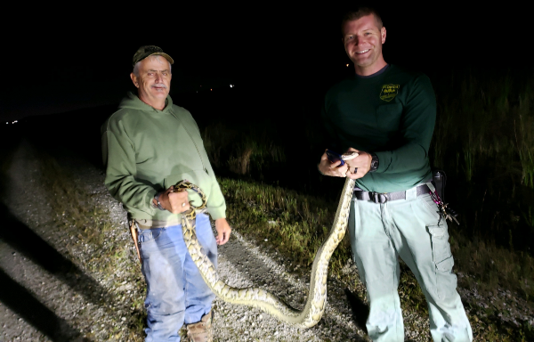 two men holding a python