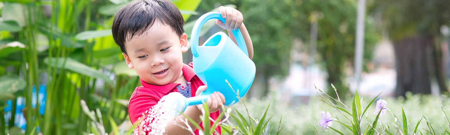 boy watering plants with watering can