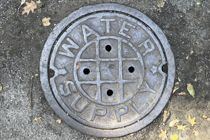 Round metal manhole cover labeled Water Supply
